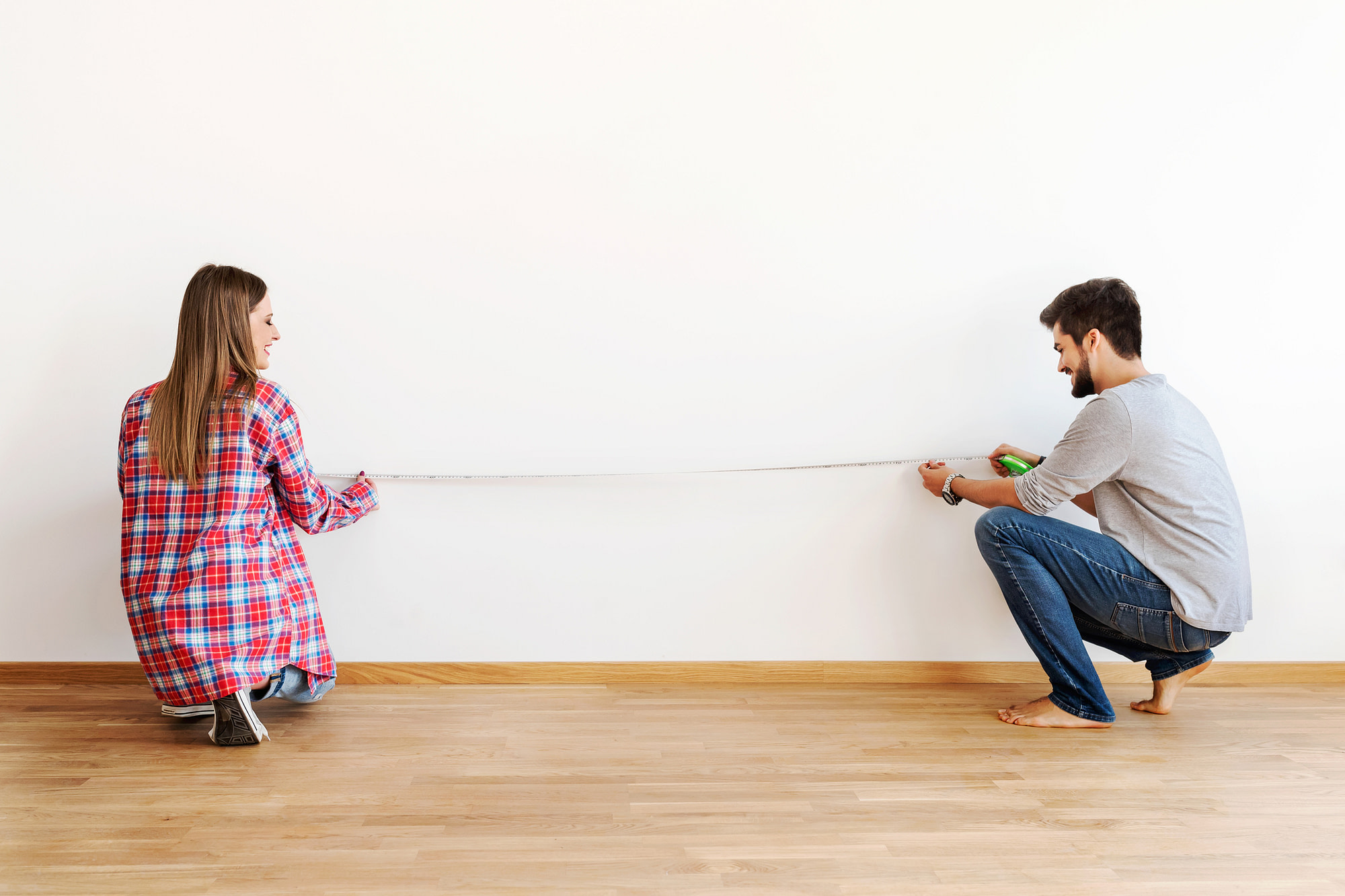 Couple in empty apartment measuring walls